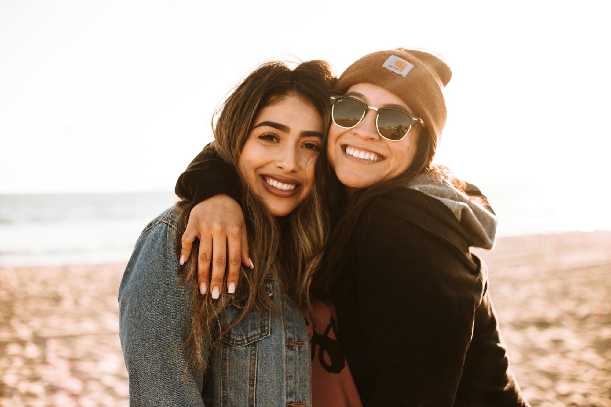 Two friends hugging and smiling on a sunny beach