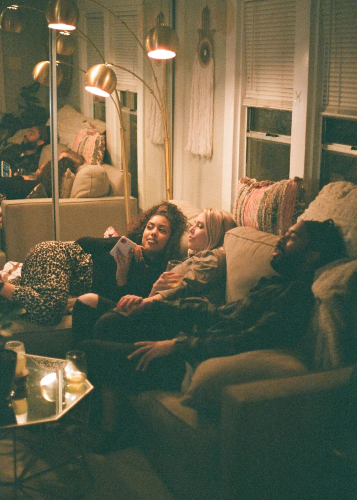Friends relaxing together on a couch at home in the evening